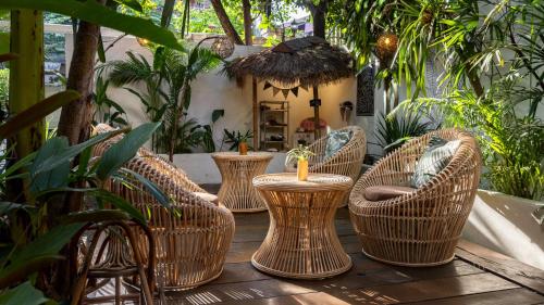 a group of wicker chairs and tables on a deck at Babel Siem Reap Guesthouse in Siem Reap