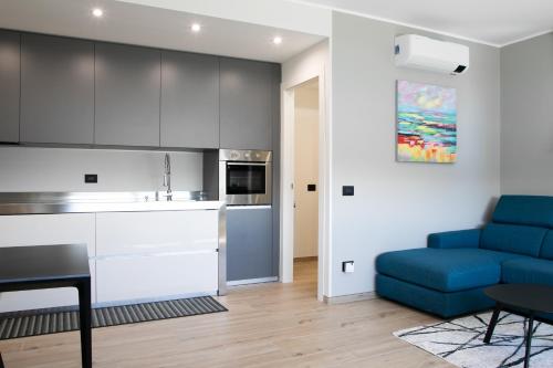a living room with a blue couch and a kitchen at Casa del lago in Oggebbio