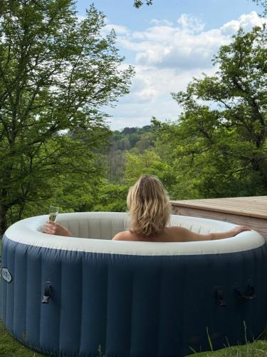 a woman in a hot tub with a glass of wine at EcoLodge Libellule romantique pour amoureux in Cazats