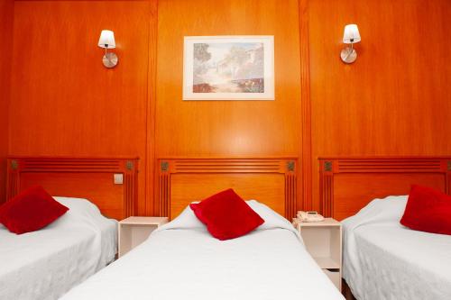 a room with two beds with red pillows on them at Hôtel du Mont Blanc in Paris