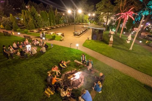 a group of people sitting around a fire in a park at night at Willa Biały Dom - Aquapark Panorama Morska All Inclusive in Jarosławiec