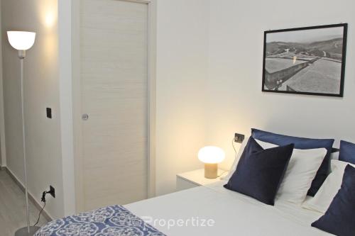 a bedroom with a bed with blue and white pillows at Casa Cavour by Propertize - centro storico in Pachino