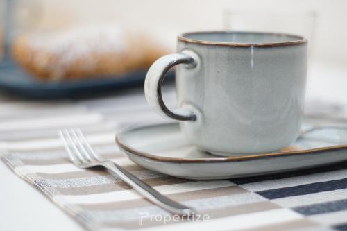 a cup on a plate with a fork on a table at Casa Cavour by Propertize - centro storico in Pachino