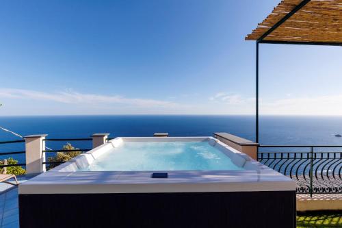 a hot tub on a balcony with the ocean in the background at Villa Le Porpore in Furore
