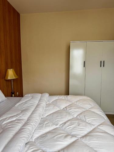 a large white bed in a bedroom with a cabinet at Home Away from Home in Kigali