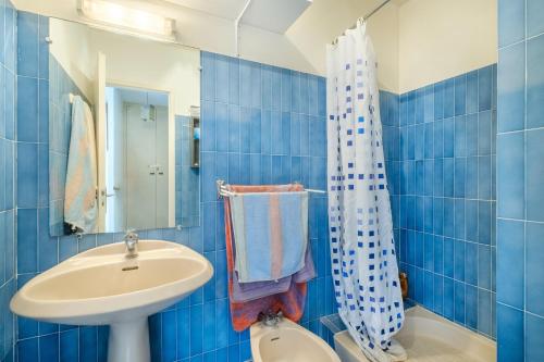 La salle de bains est pourvue de carrelage bleu, d'un lavabo et de toilettes. dans l'établissement Grand studio Les Masters, à Mandelieu-la-Napoule
