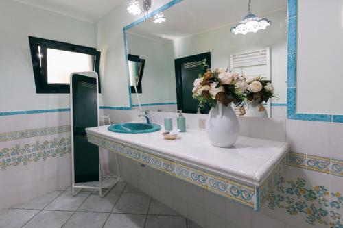 a bathroom with a sink and a vase with flowers on it at Villa Le Porpore in Furore
