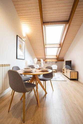 a dining room with a table and chairs and a skylight at Cámara By Silastur in Avilés