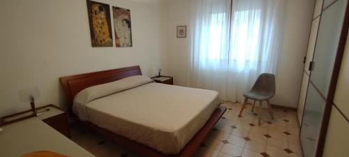 a bedroom with a bed and a chair and a window at Casa Marilù in Alghero