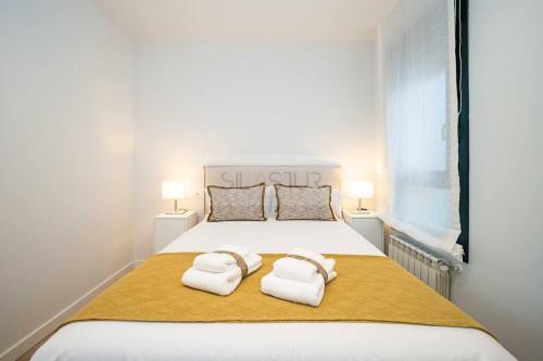 a bedroom with a large white bed with towels on it at Cámara By Silastur in Avilés
