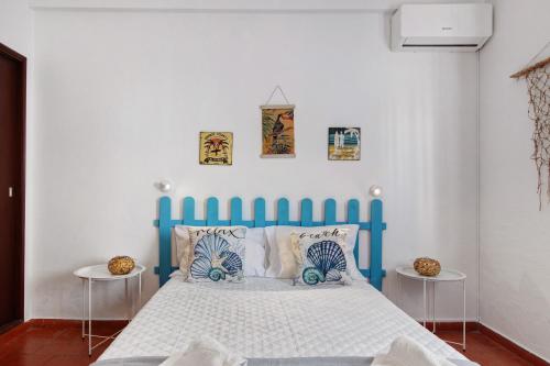 a blue bed in a white room with two tables at Casa Amarela in Tavira