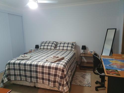NarangbaNarnie's Place in Narangba - Relaxed Space with Breakfast的卧室里有一张床，上面铺着格子毯子，还有一张书桌