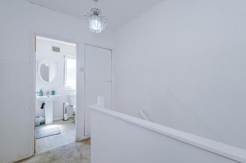 a white bathroom with a staircase and a mirror at Stylish 3 bed house sleeps 5 free parking in Dudley Hill