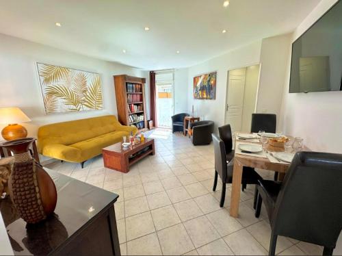un salon avec un canapé jaune et une table dans l'établissement T3 en 3 étoiles de plain-pied, climatisé, terrasse, jardinet et parking, très calme, à Pomérols