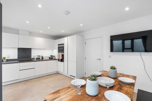 a kitchen with white cabinets and a wooden table at Bright and Modern 3 bed Seaside escape sleeps 5 in Brighton & Hove