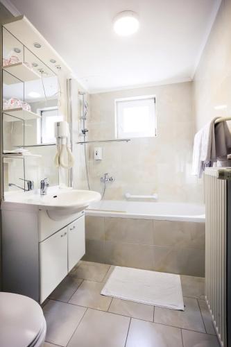 a white bathroom with a tub and a sink at Hotel Garten in Slavonski Brod