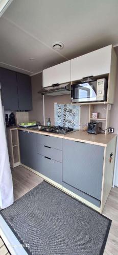une cuisine avec des armoires blanches et un comptoir dans l'établissement Mobil home 6 pers - Camping 4 étoiles - Sarzeau, à Sarzeau