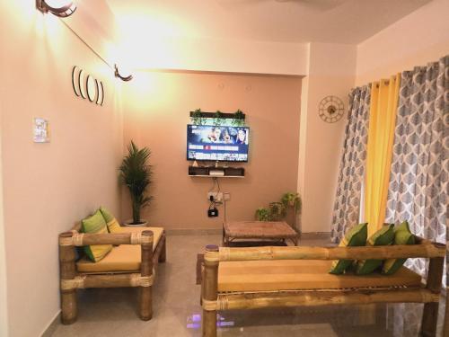 a living room with two chairs and a tv at Amaar Ghar in Guwahati