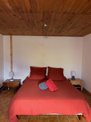 - une chambre avec un lit avec des draps rouges et deux lampes dans l'établissement Chez Corinne, à Alex