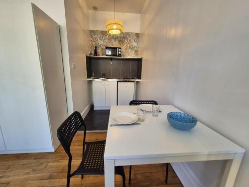 a white dining room table with two chairs and a bowl on it at Les Loges Du Beffroi - La Cloche Dorée & Parking privé in Arras