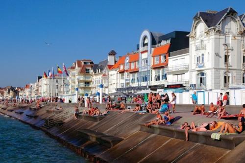 a group of people sitting on the beach near the water at Au Bocage Parfumé Gîte La Cigaline in Wirwignes