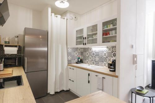 a kitchen with white cabinets and a stainless steel refrigerator at Duplex Cosy Glam au Centre-Ville secteur piéton * WiFi * Calme in Troyes