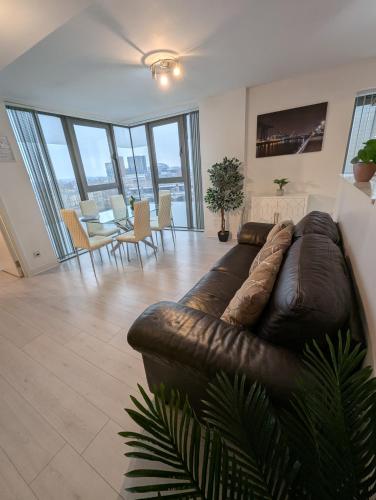 a living room with a brown leather couch and a table at Glasgow City Centre Waterfront Apartment in Glasgow