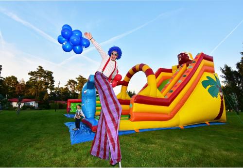 a woman is standing on a infront of a playground at Willa Biały Dom - Aquapark Panorama Morska All Inclusive in Jarosławiec