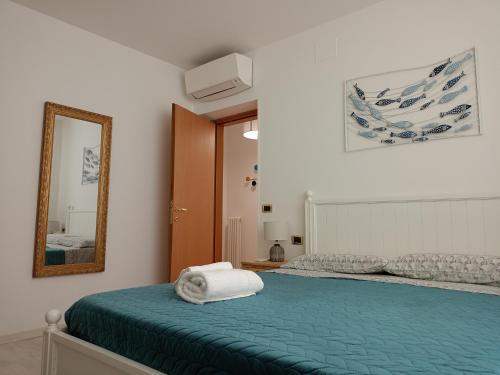 a bedroom with a bed with a green blanket and a mirror at Da Margot - Appartamento al mare in Grottammare