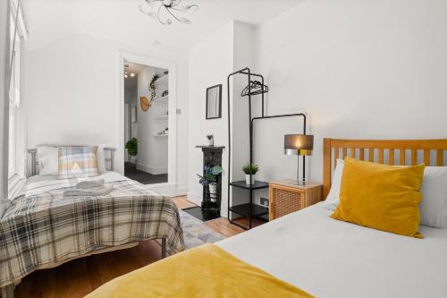 a bedroom with two beds and a mirror at Lovely 4 Bedroom London Home with Free Parking, Garden, WiFi By Roost Accommodation in Kingston upon Thames