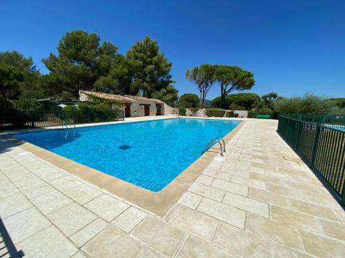 une piscine avec de l'eau bleue dans une cour dans l'établissement Coquillages et Crustacés - Piscine & Tennis, à Gassin