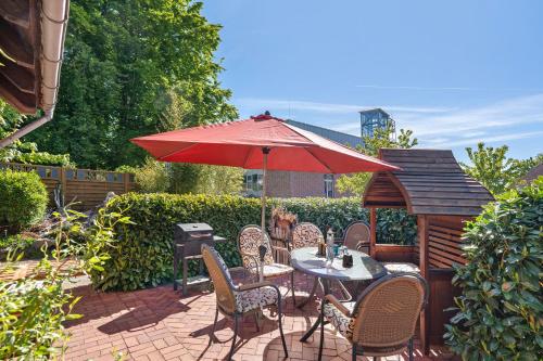 a patio with a table and a red umbrella at Ferienhaus Ankerglück in Lensahn