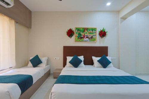 a bedroom with two beds with blue and white pillows at The Castle Crown - Hotel Lord Krishna Dham in Dwarka