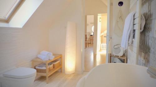 La salle de bains blanche est pourvue de toilettes et d'un couloir. dans l'établissement Kercolette, maison avec piscine non chauffée proche des plages, à Erdeven