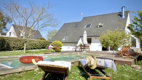 une maison avec une piscine avec deux chaises et une maison dans l'établissement Kercolette, maison avec piscine non chauffée proche des plages, à Erdeven