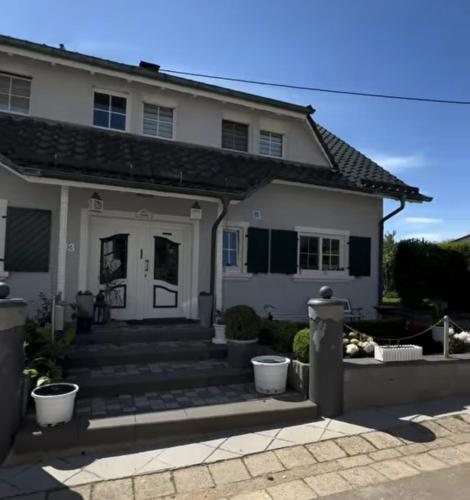 a white house with a front porch and stairs at Ferienwohnung Aloysia am Saarlandradweg in Merzig