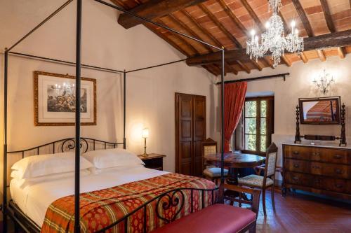 a bedroom with a bed and a table and a chandelier at Castello Di Tornano Wine Relais in Gaiole in Chianti