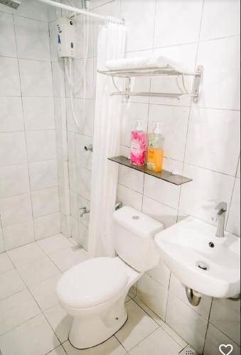a white bathroom with a toilet and a sink at Melvo's Homestay in Puerto Princesa City