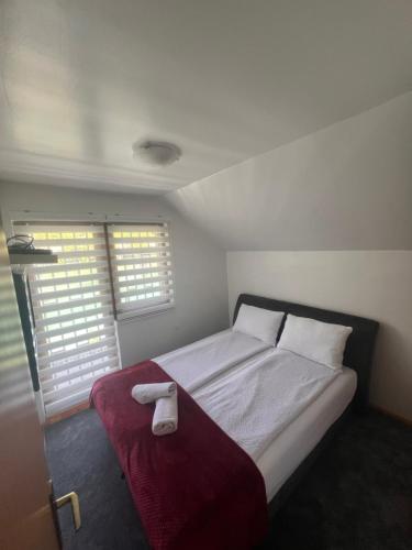 a bedroom with a bed with a red blanket and two windows at Vila sa bazenom Lily in Konjic