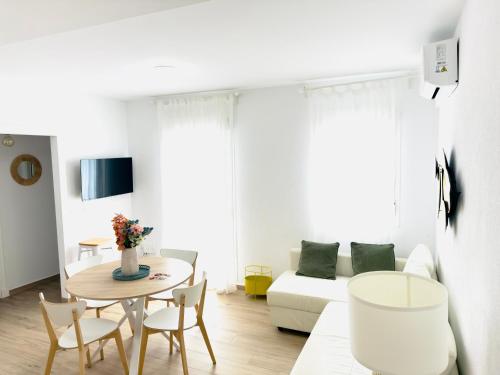 a living room with a table and a couch at Alojamiento Erytheia, tranquilo, a 150 metros de la playa y pleno casco histórico in Conil de la Frontera