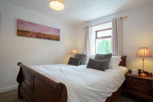 Un dormitorio con una cama con sábanas blancas y una ventana. en Morton Cottage, en Thornhill