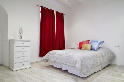 a bedroom with red curtains and a bed and a dresser at Loft con encanto en el corazón histórico de Peralada in Peralada