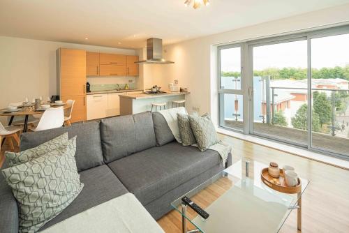 a living room with a gray couch and a kitchen at Stylish 2-Bed with Stunning View in London