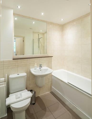 a bathroom with a toilet and a sink and a bath tub at Stylish 2-Bed with Stunning View in London