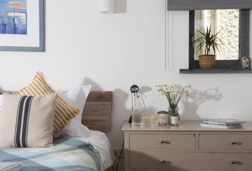 a bedroom with a bed with a dresser and a mirror at The Perch Studio in Polzeath