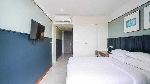 a bedroom with a white bed and a flat screen tv at Marina House MUAYTHAI Ta-iad Phuket in Chalong 