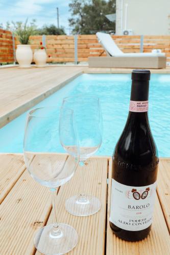 a bottle of wine and two glasses next to a swimming pool at Moute House by Corfuescapes in Ágioi Doúloi