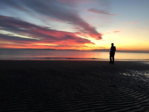 a person standing on the beach at sunset at Irvine Guest House in Irvine