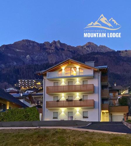a large white building with a mountain in the background at Mountain Lodge in San Lorenzo in Banale