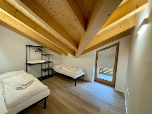 a room with two beds and a wooden ceiling at Mountain Lodge in San Lorenzo in Banale